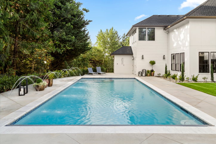 A luxurious backyard swimming pool surrounded by beautifully landscaped greenery showcasing a serene and elegant outdoor space. | ASP - America's Swimming Pool Company of Nashville