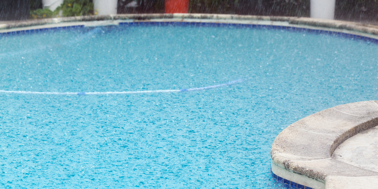Heavy rain falls into a outdoor home pool.