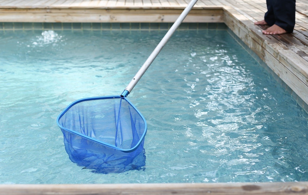 Person cleaning pool with pool leaf skimmer